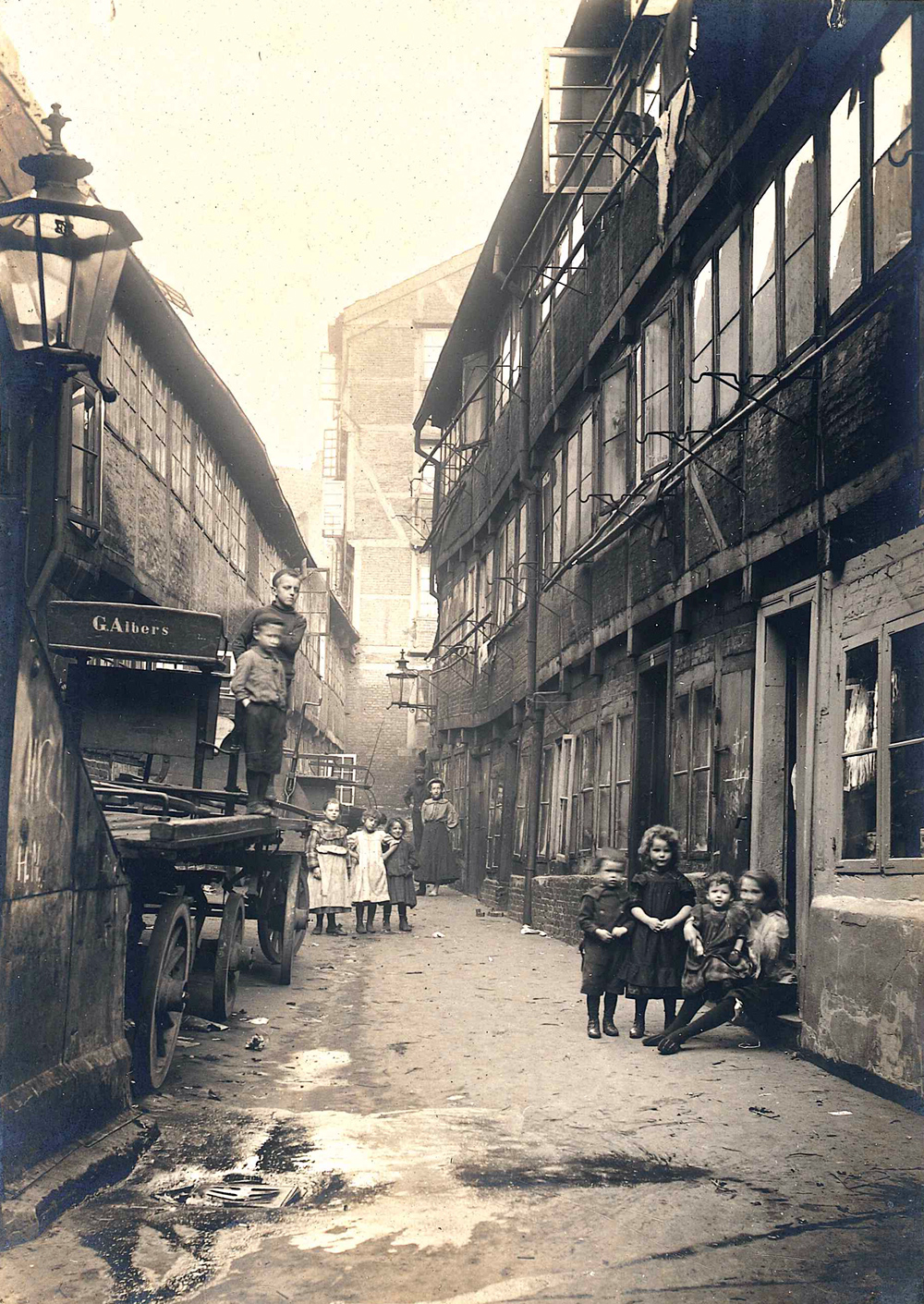 schmale Gasse mit Fachwerkhäusern, Bewohner auf der Straße
