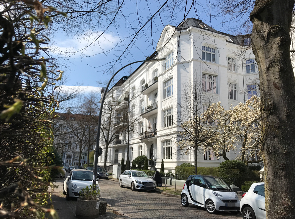 Straße mit weißem Mehrfamilienhaus